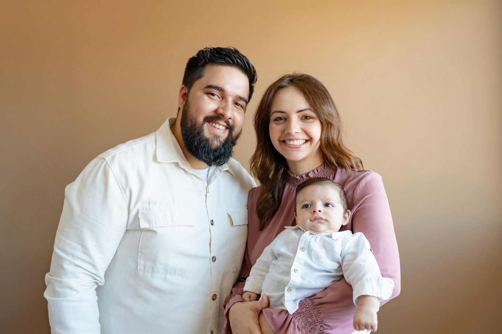 Una pareja sonriente sosteniendo a su bebé